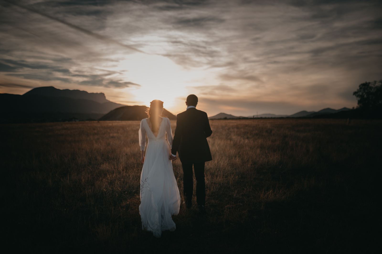 Novios caminando de espaldas por un campo al atardecer en Huesca