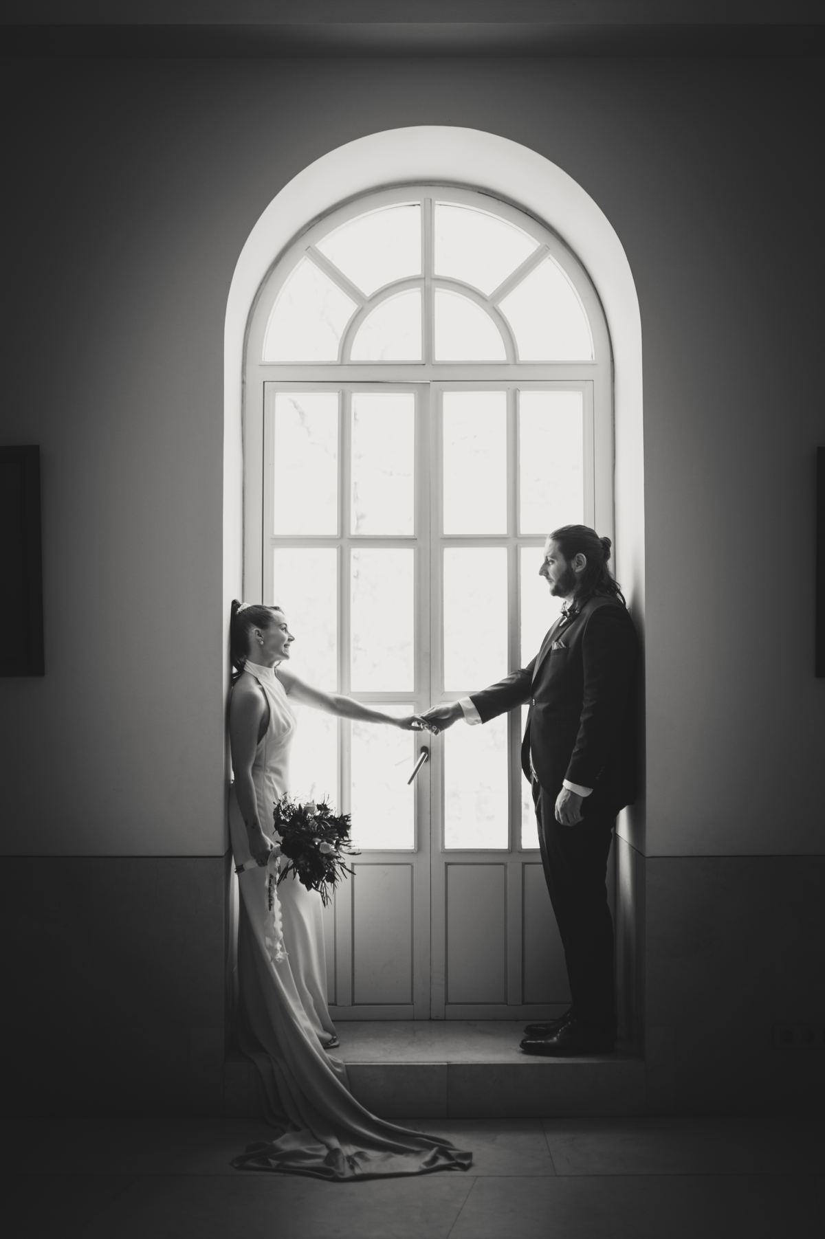 Novios frente a un gran ventanal en blanco y negro
