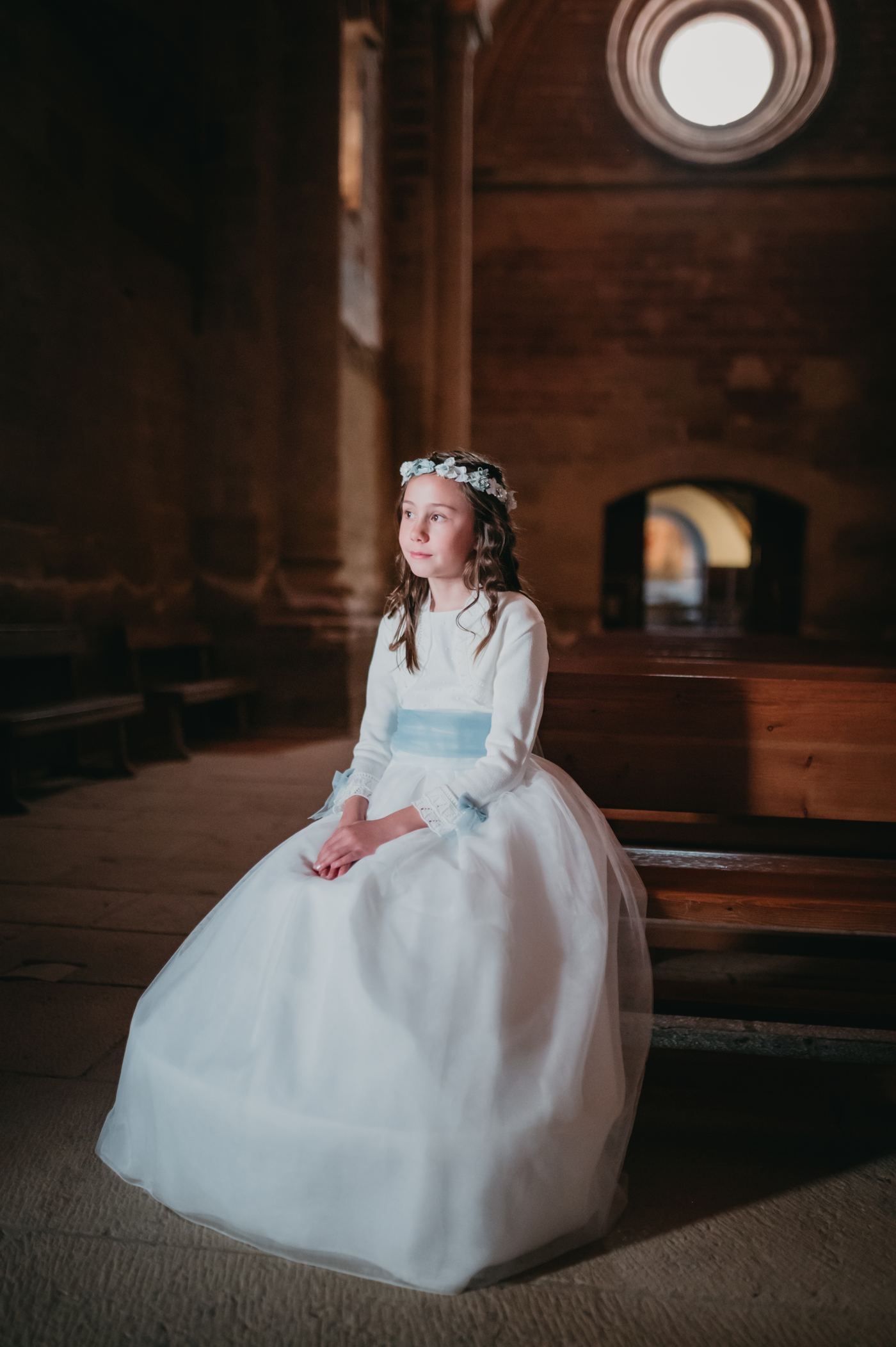 Niña de comunión sentada en el interior de una iglesia