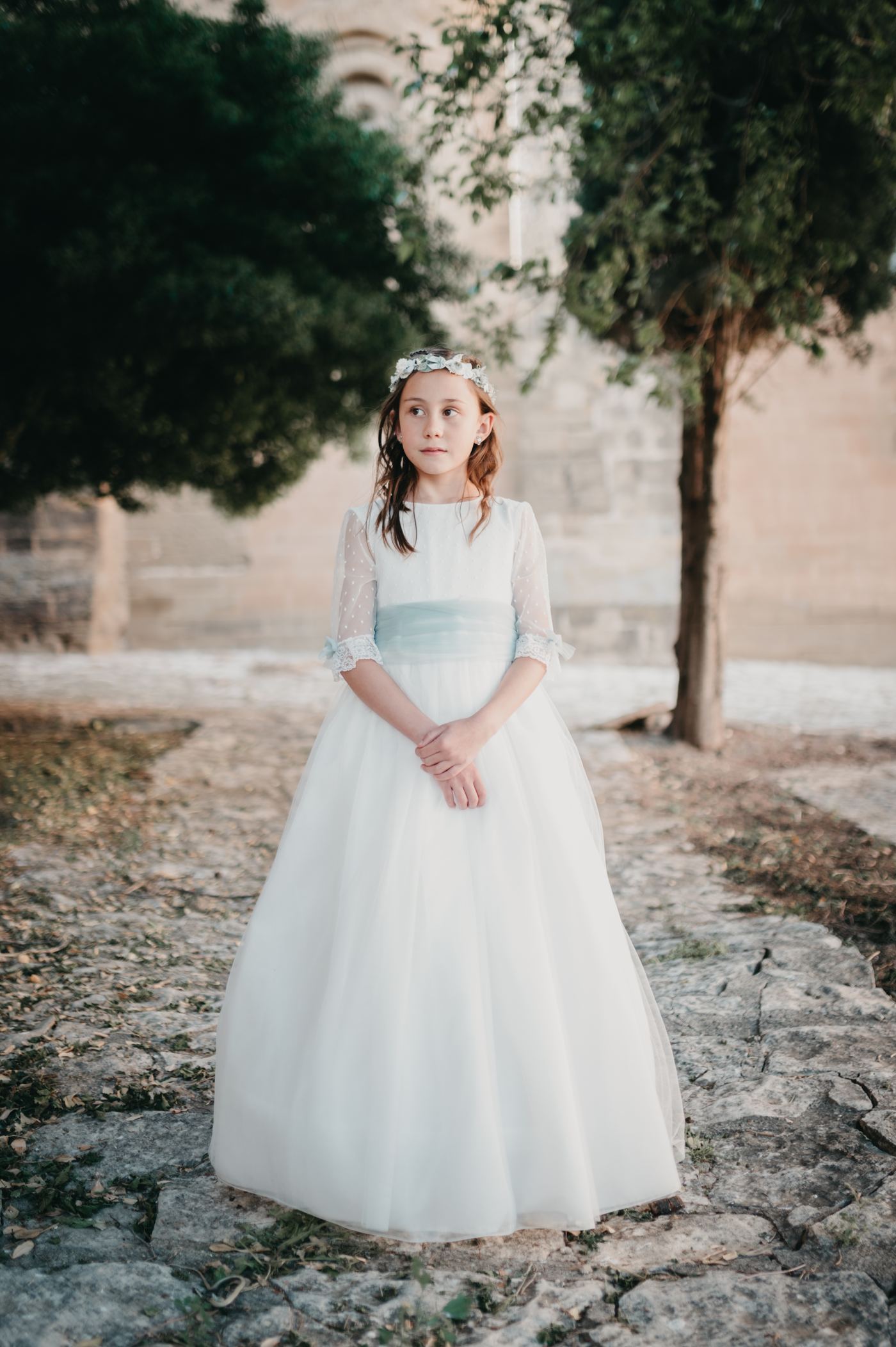 Niña de comunión en un jardín de piedra