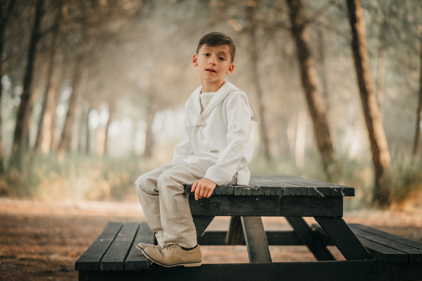 Niño de comunión sentado en una mesa de picnic