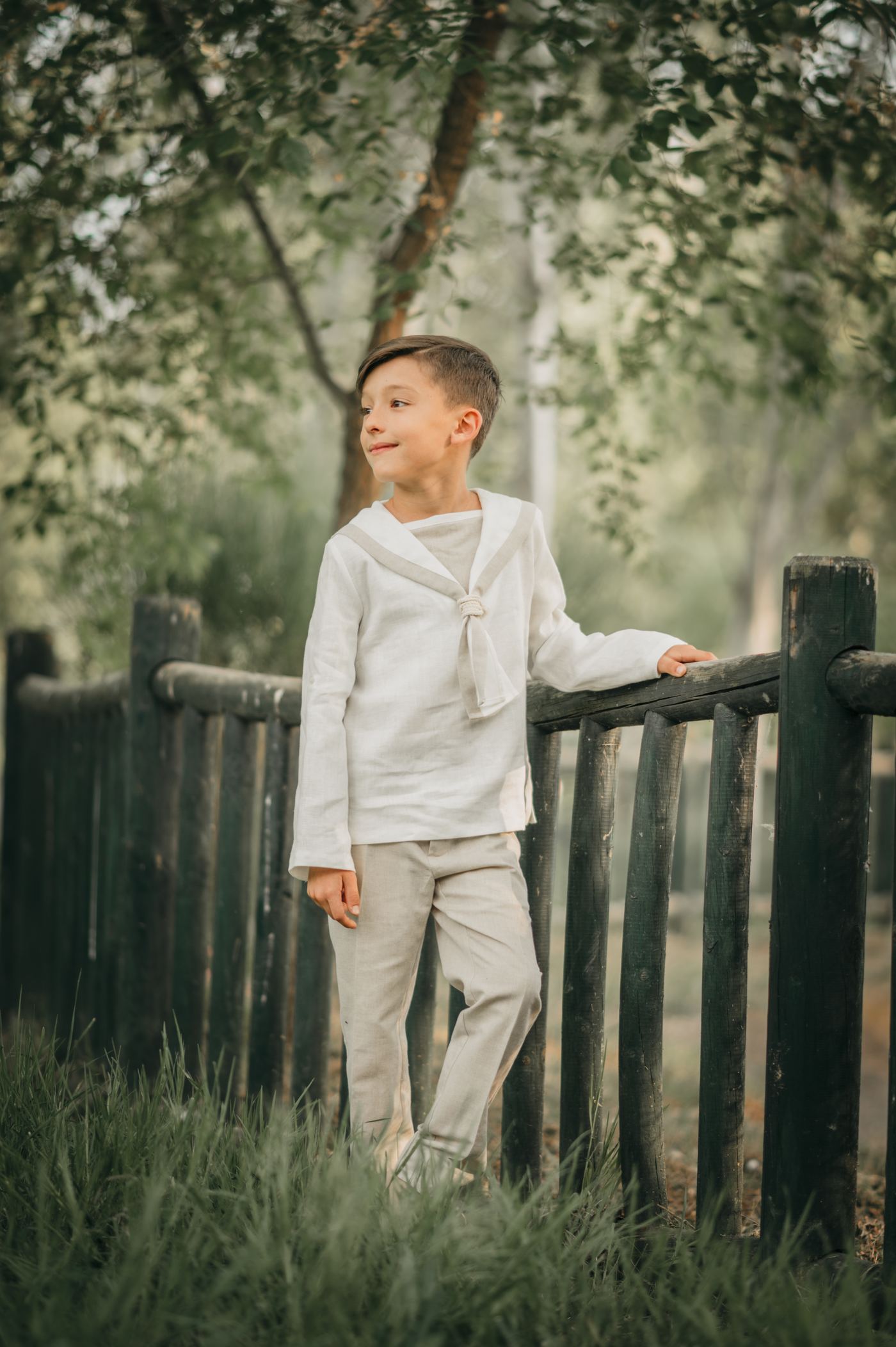 Niño de comunión junto a una valla de madera