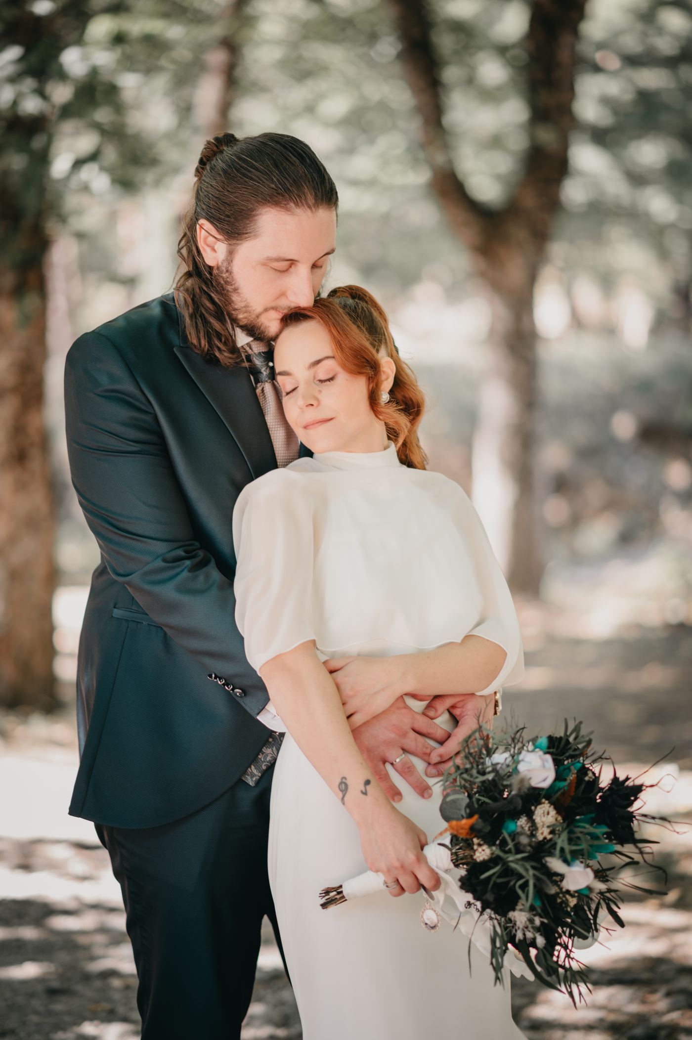 El novio abraza a la novia en el bosque