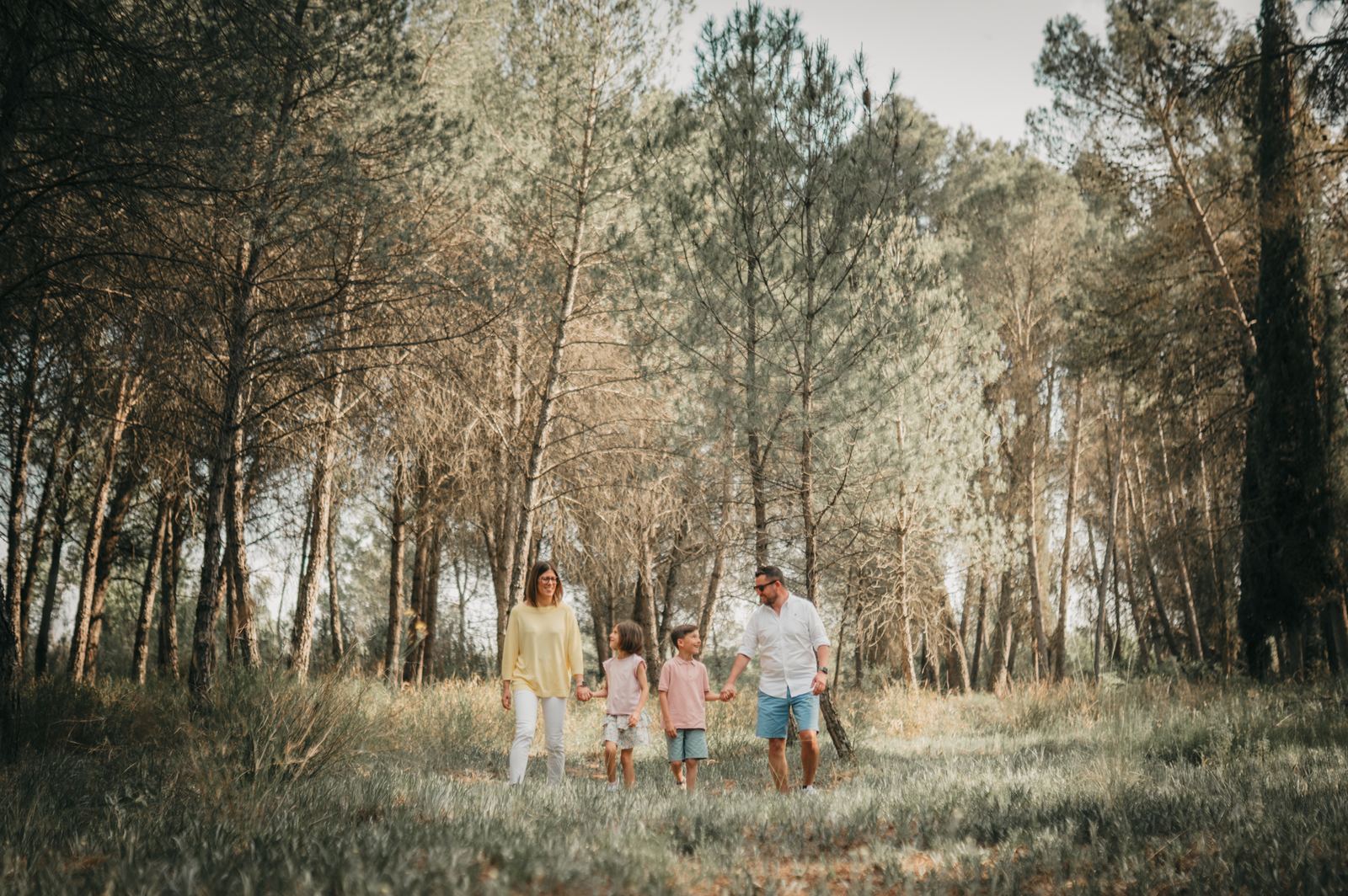 Familia paseando de la mano por un pinar