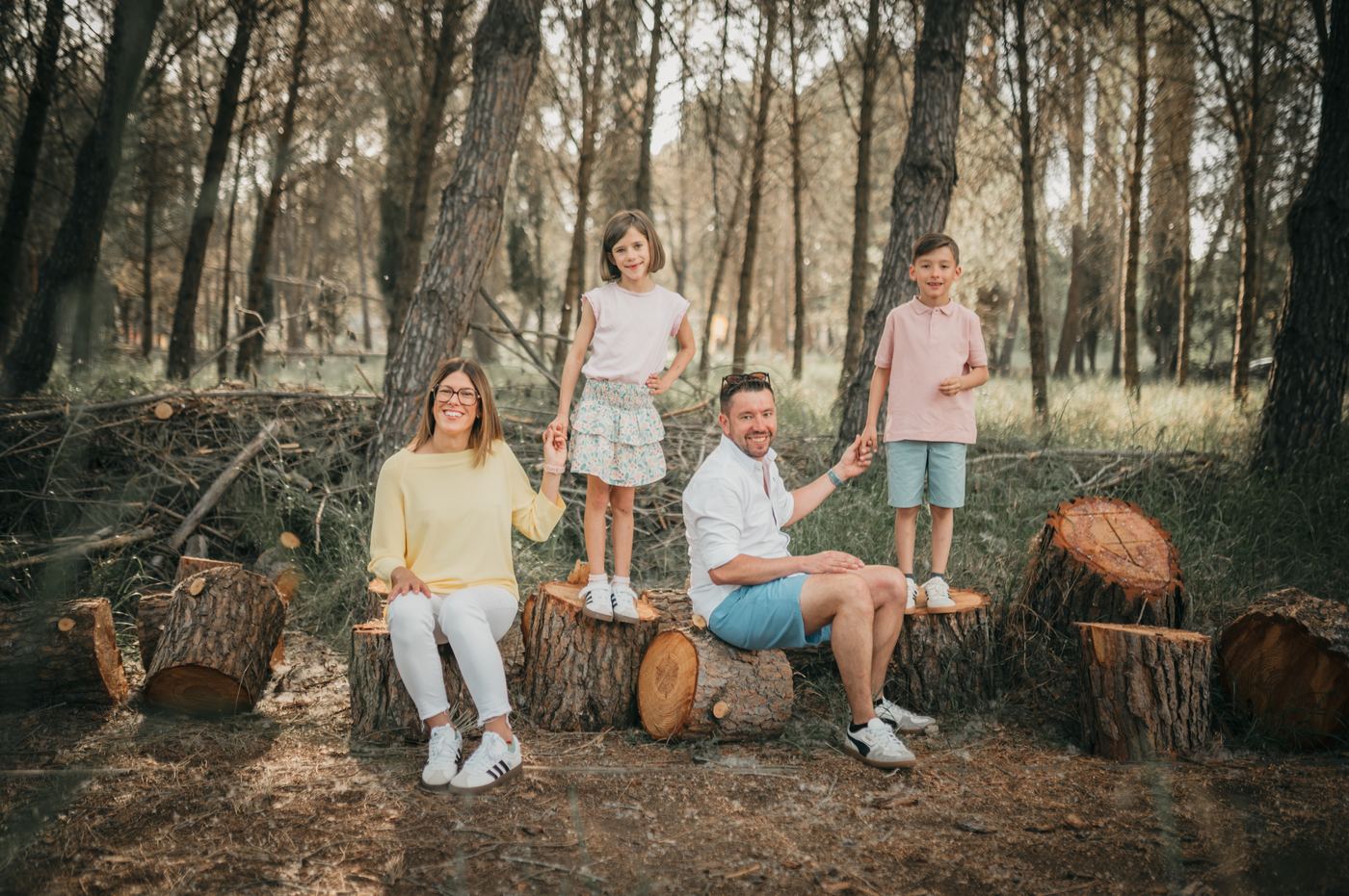 Familia sentada sobre troncos en el pinar